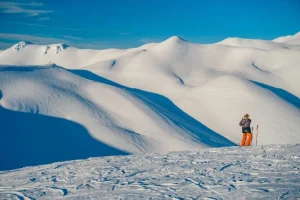 Persona caminando en la nieve con equipo en Antillanca, paisaje nevado de fondo